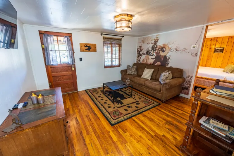 Cassidy Suite two bedroom cabin at The Amoretti Hotel in Dubois, Wyoming, the living area with a sofa, coffee table, and a doorway into a bedroom.